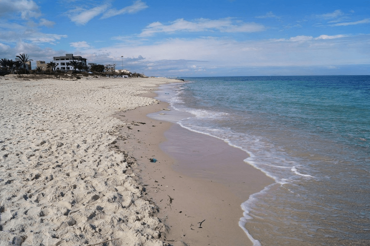 picture from playa de la torre derribada with the sea on the right and multiple buildings on the left