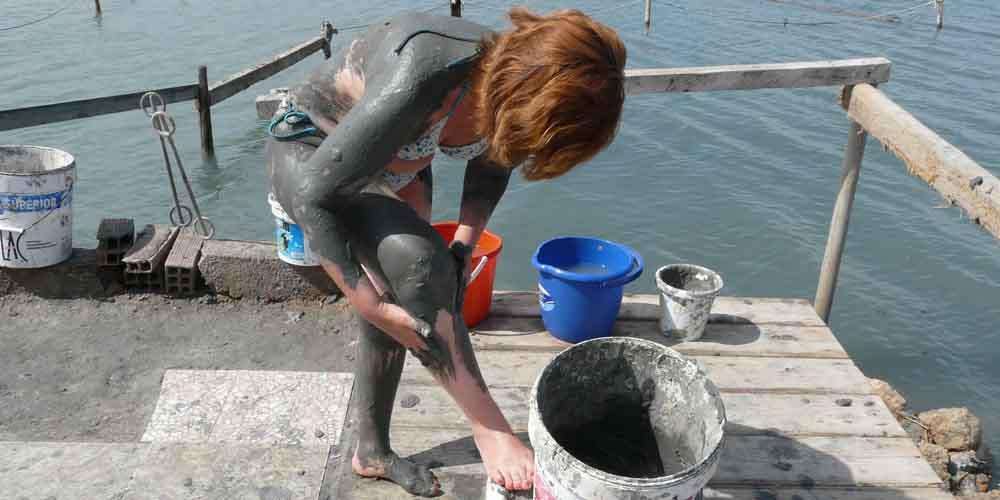 A girl covering her body with mud in the mud baths of Murcia