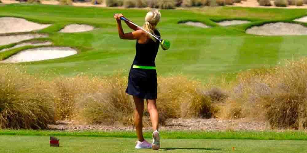 A girl hitting a ball in the golf course of the Hacienda Riquelme
