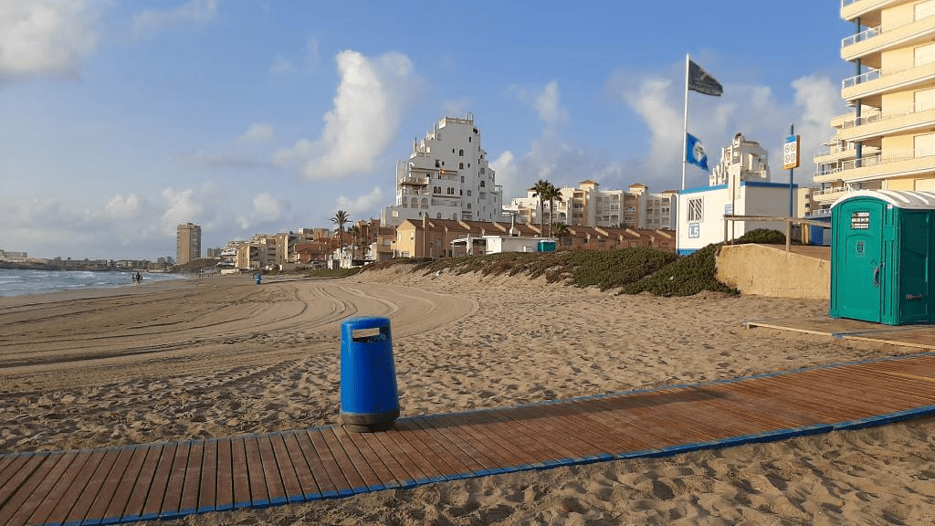 image of a wooden path in the sand along with people walking on the background