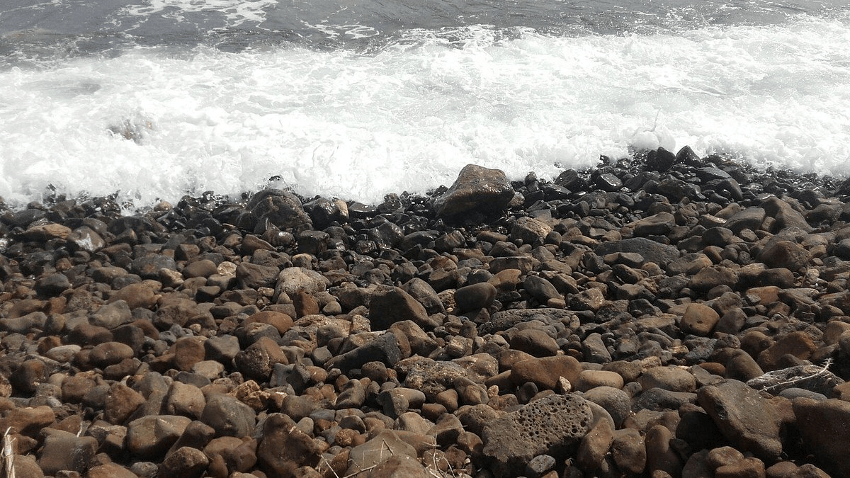 image of the beach showing the waves hitting the rocks