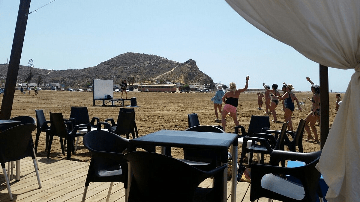 picture taken from a restaurant showing people doing dance classes at the beach in Spain
