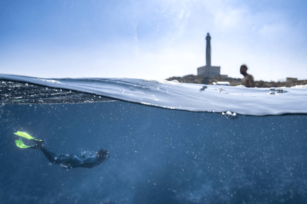 image of a person snorkeling and the other one swimming at the beach