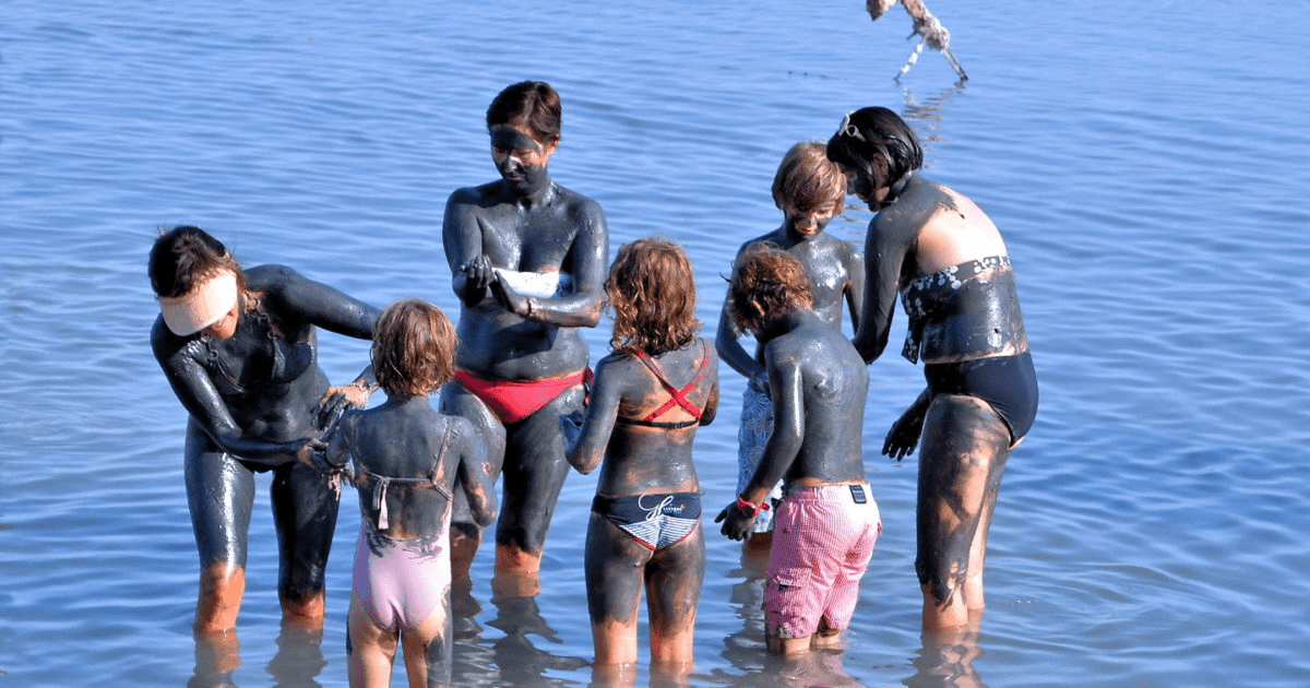 image of a family doing a mud bath at the beach